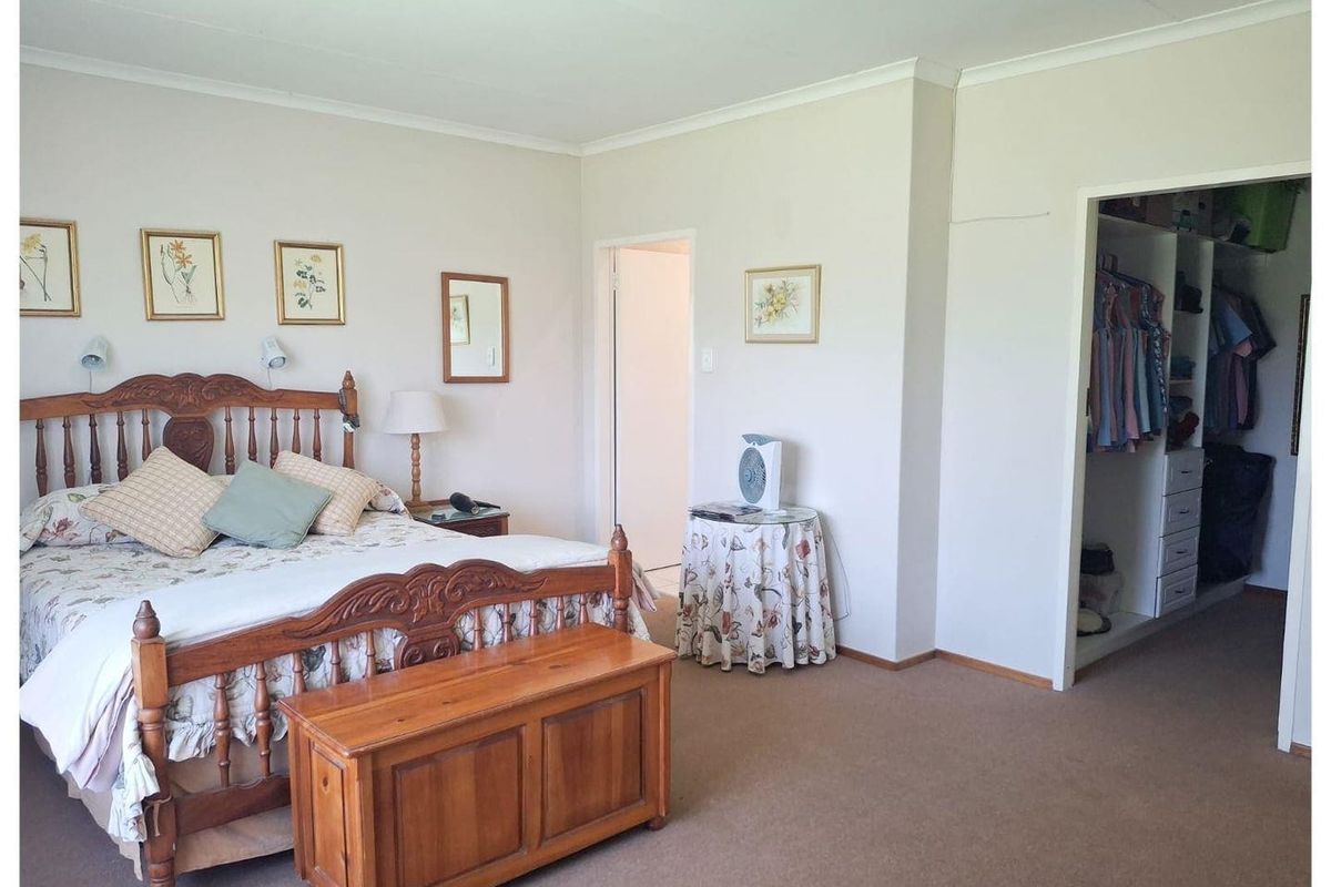 Spacious bedroom featuring neutral wall finishes, carpeted flooring, and an integrated walk-in closet area with built-in shelving and hanging space.