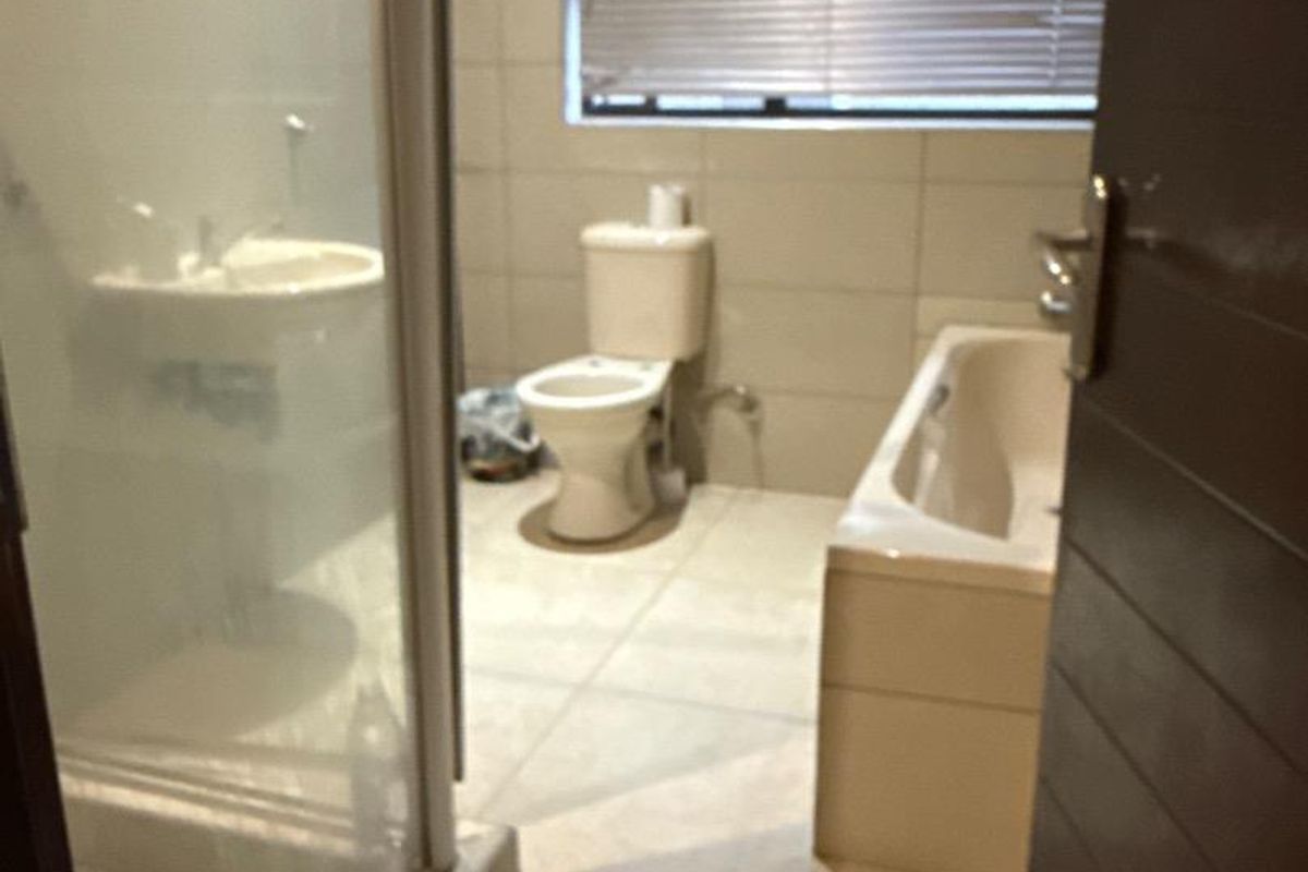A functional bathroom featuring a shower enclosure, pedestal basin, bathtub, and tiled finishes throughout.