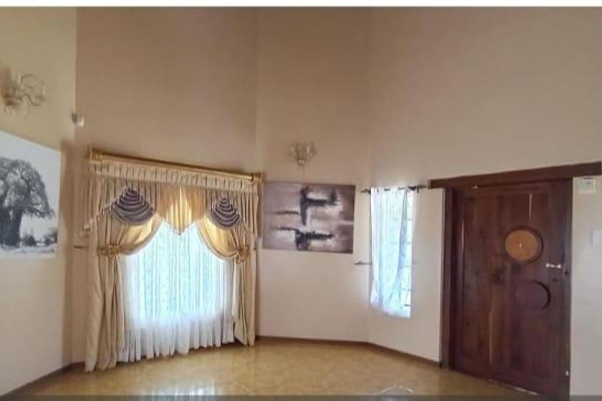 Spacious living area featuring high vaulted ceilings, tiled flooring, and a solid timber entrance door with decorative detailing.