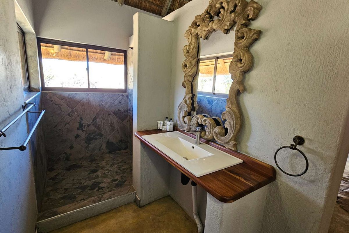 A bathroom featuring a built-in vanity with a wooden countertop, a modern basin, and a walk-in shower with tiled walls.