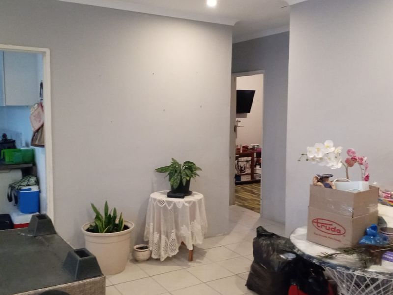 A living area featuring tiled flooring and recessed lighting, with an open transition to the kitchen and adjacent rooms.