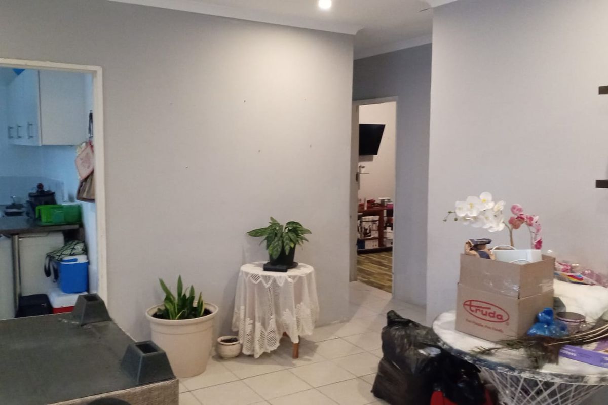 A living area featuring tiled flooring and recessed lighting, with an open transition to the kitchen and adjacent rooms.