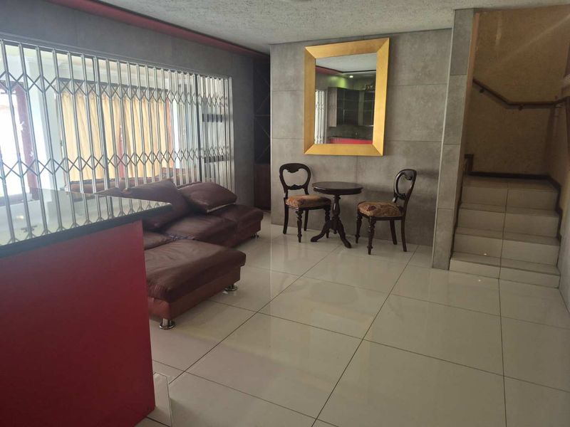 Living area featuring large format floor tiles, a built-in bar counter, and a staircase leading to the upper level.