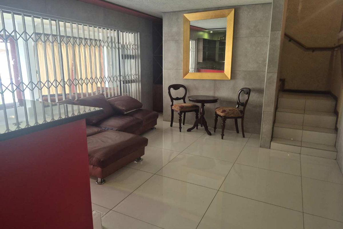 Living area featuring large format floor tiles, a built-in bar counter, and a staircase leading to the upper level.