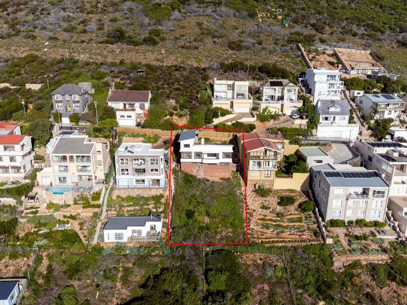 Aerial view of a residential property plot situated on a hillside, highlighting the sloped terrain and surrounding neighborhood context.