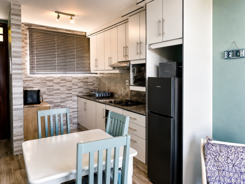 A functional kitchen featuring built-in cabinetry, granite countertops, a gas hob with extractor fan, and a tiled backsplash, complemented by modern finishes.
