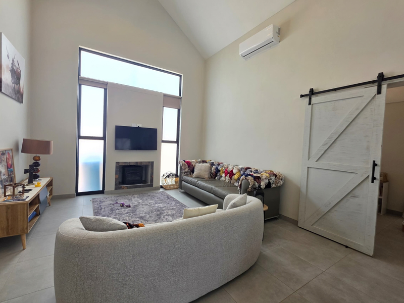 Spacious living room featuring a vaulted ceiling, tiled flooring, a built-in fireplace, and a distinctive barn-style sliding door.