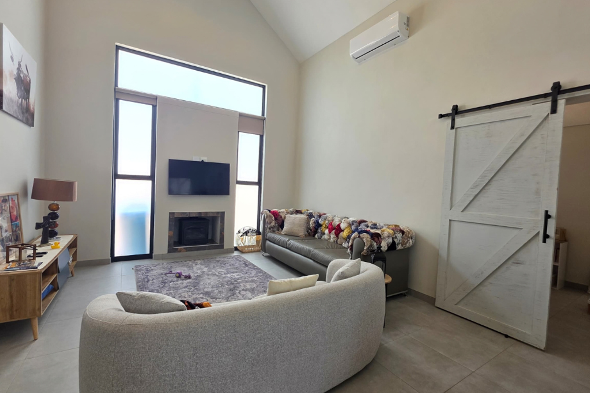 Spacious living room featuring a vaulted ceiling, tiled flooring, a built-in fireplace, and a distinctive barn-style sliding door.