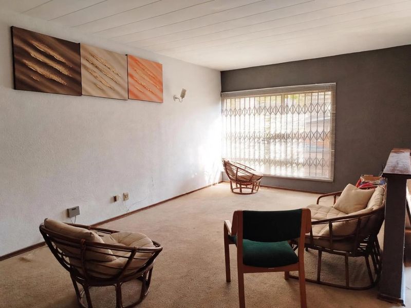 A living room featuring carpeted flooring, a tongue and groove ceiling, and a security gate over the window.