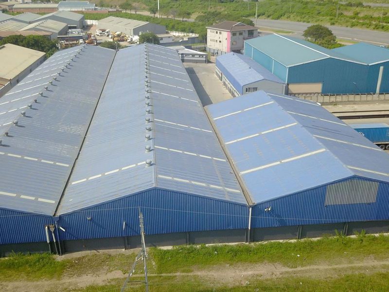 Aerial view of a large industrial warehouse complex featuring multiple corrugated metal roof sections and paved yard space for logistics and storage.