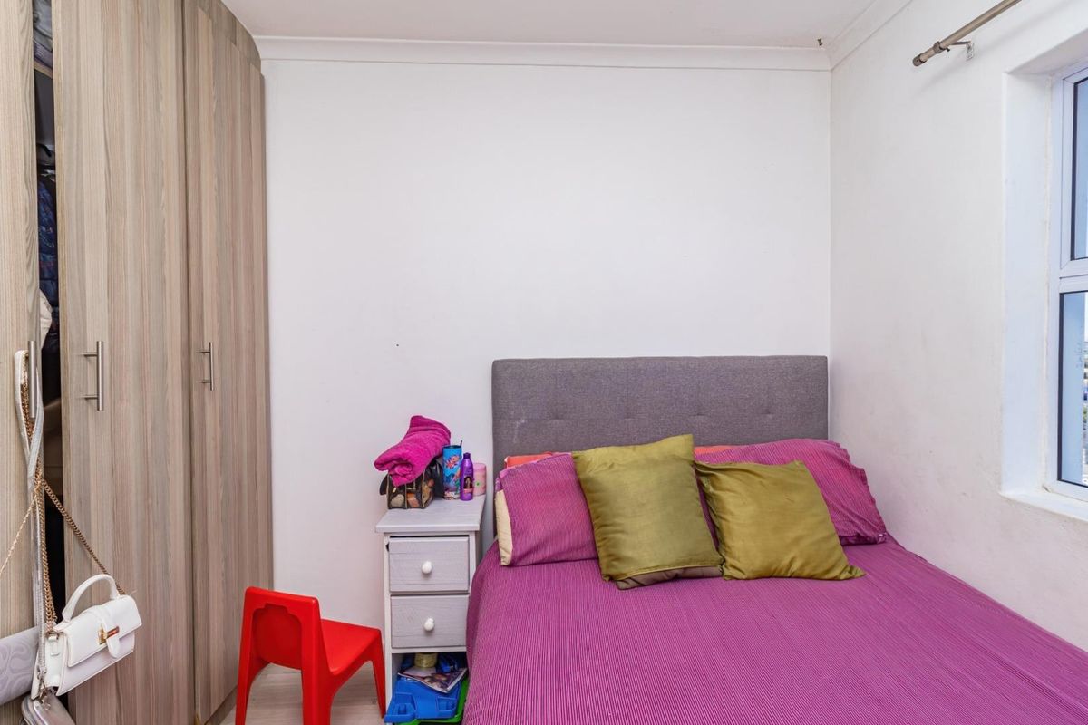 A bedroom featuring built-in wooden wardrobes and a window, providing a functional and compact living space.