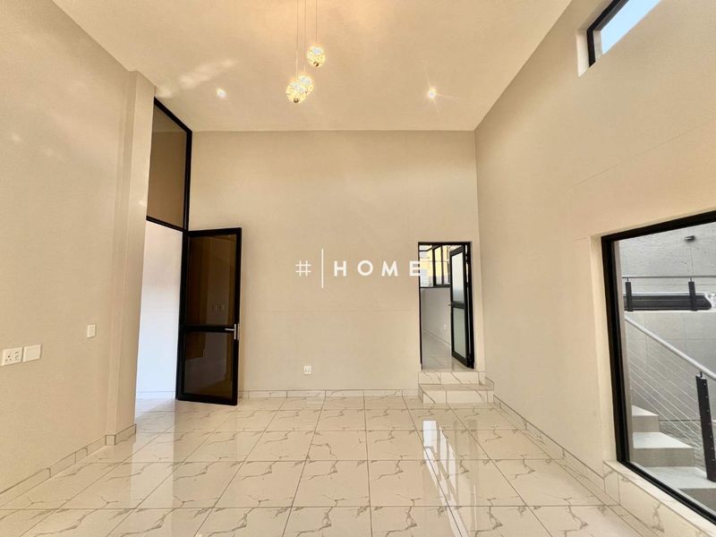 A bright, spacious living area featuring high ceilings, modern porcelain tile flooring, and large aluminum-framed windows that provide ample natural light.
