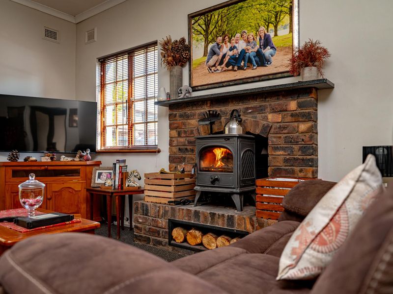 Cozy living room featuring a prominent brick fireplace with a built-in wood-burning stove and a timber-framed window.
