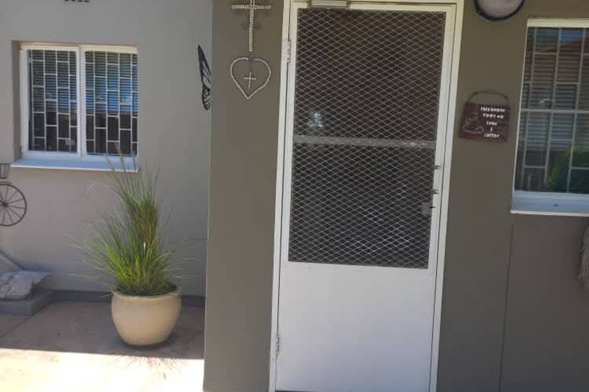 Front entrance area featuring a security gate, paved driveway, and protective awning over the doorway.