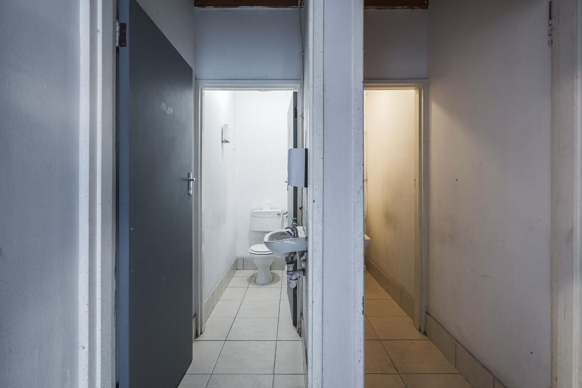 A functional industrial restroom facility featuring two separate toilet cubicles with tiled flooring and basic sanitary fixtures.