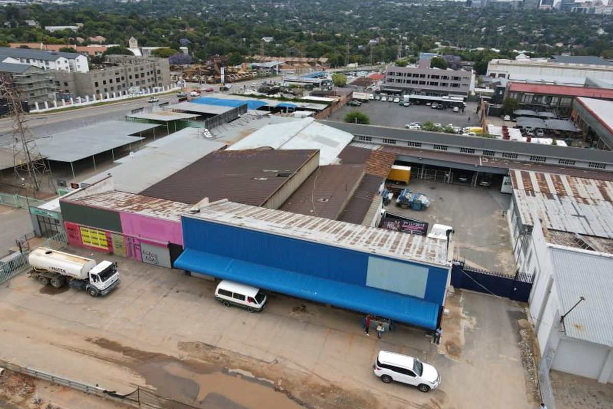 Aerial view of an industrial property complex featuring multiple warehouse units, corrugated metal roofing, and a paved parking yard.