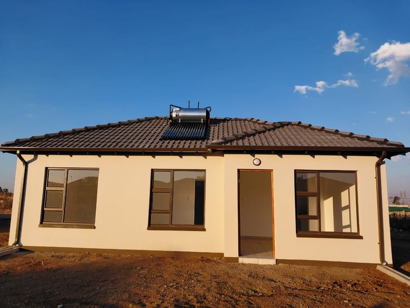 Rear view of a modern single-story house featuring a tiled roof, solar water heating system, and aluminium-framed windows.