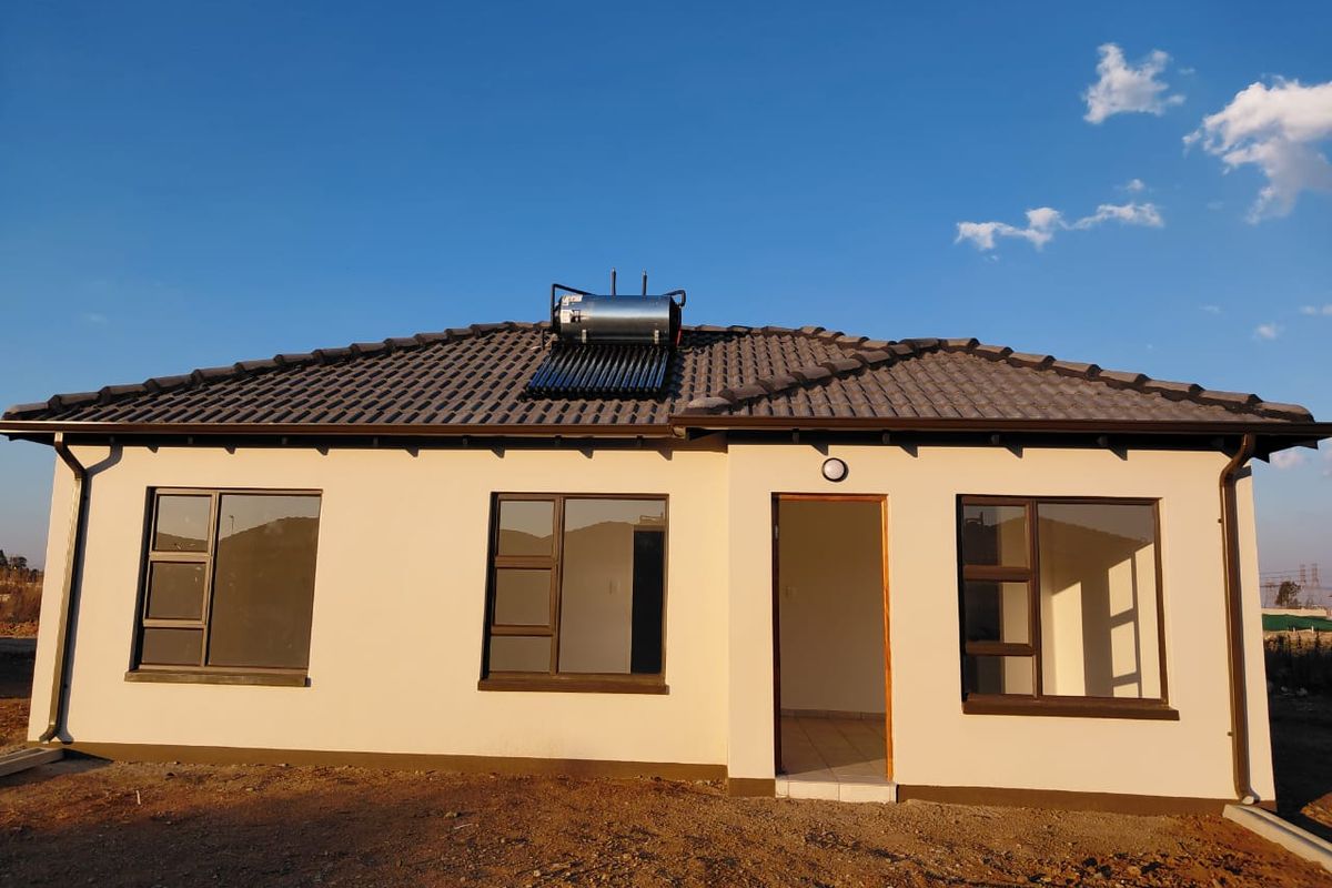 Rear view of a modern single-story house featuring a tiled roof, solar water heating system, and aluminium-framed windows.