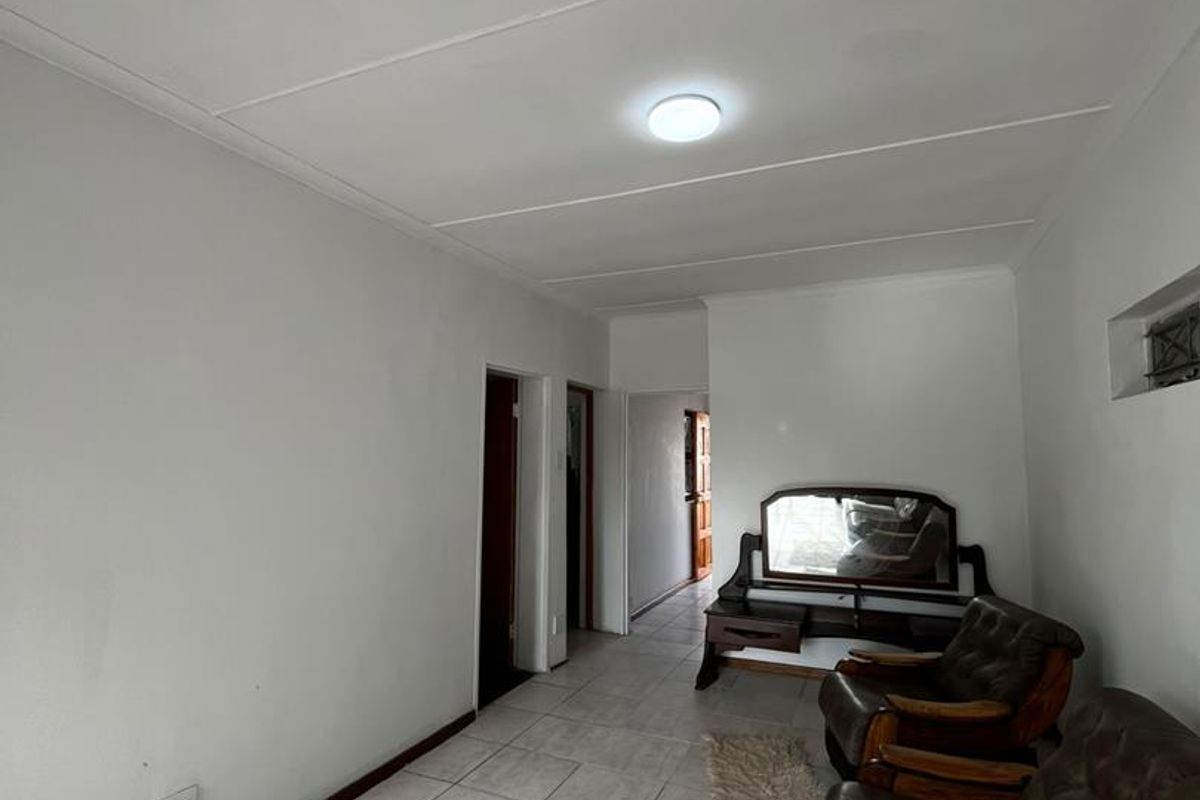 A simple living area featuring neutral tiled flooring and clean white walls, providing a functional and bright space.