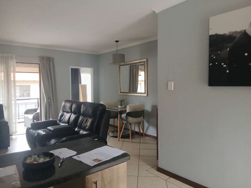 An open-plan living and dining area featuring tiled flooring, neutral wall tones, and a sliding door providing access to an outdoor balcony.