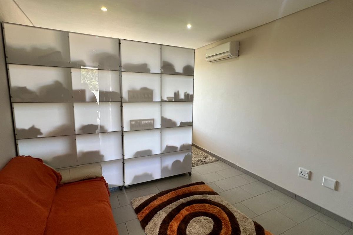 A functional living space featuring tiled flooring, recessed ceiling lighting, and a wall-mounted air conditioning unit.