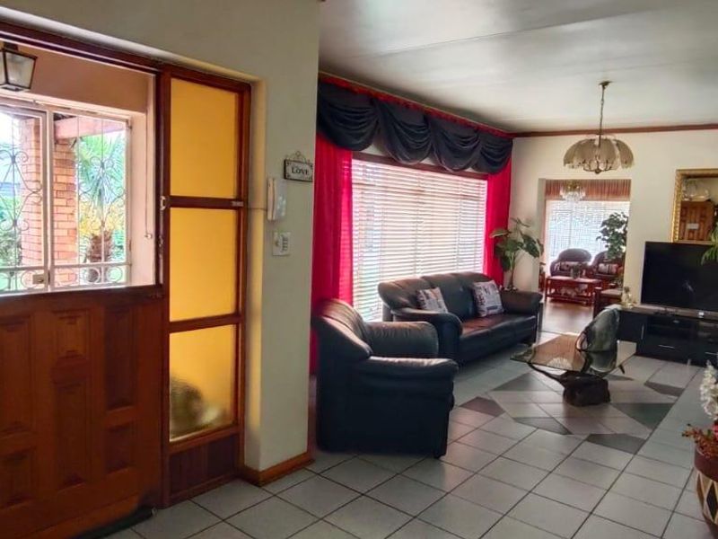 Spacious living area featuring tiled flooring and a traditional timber front door with glass sidelights, offering a bright and welcoming entrance to the home.