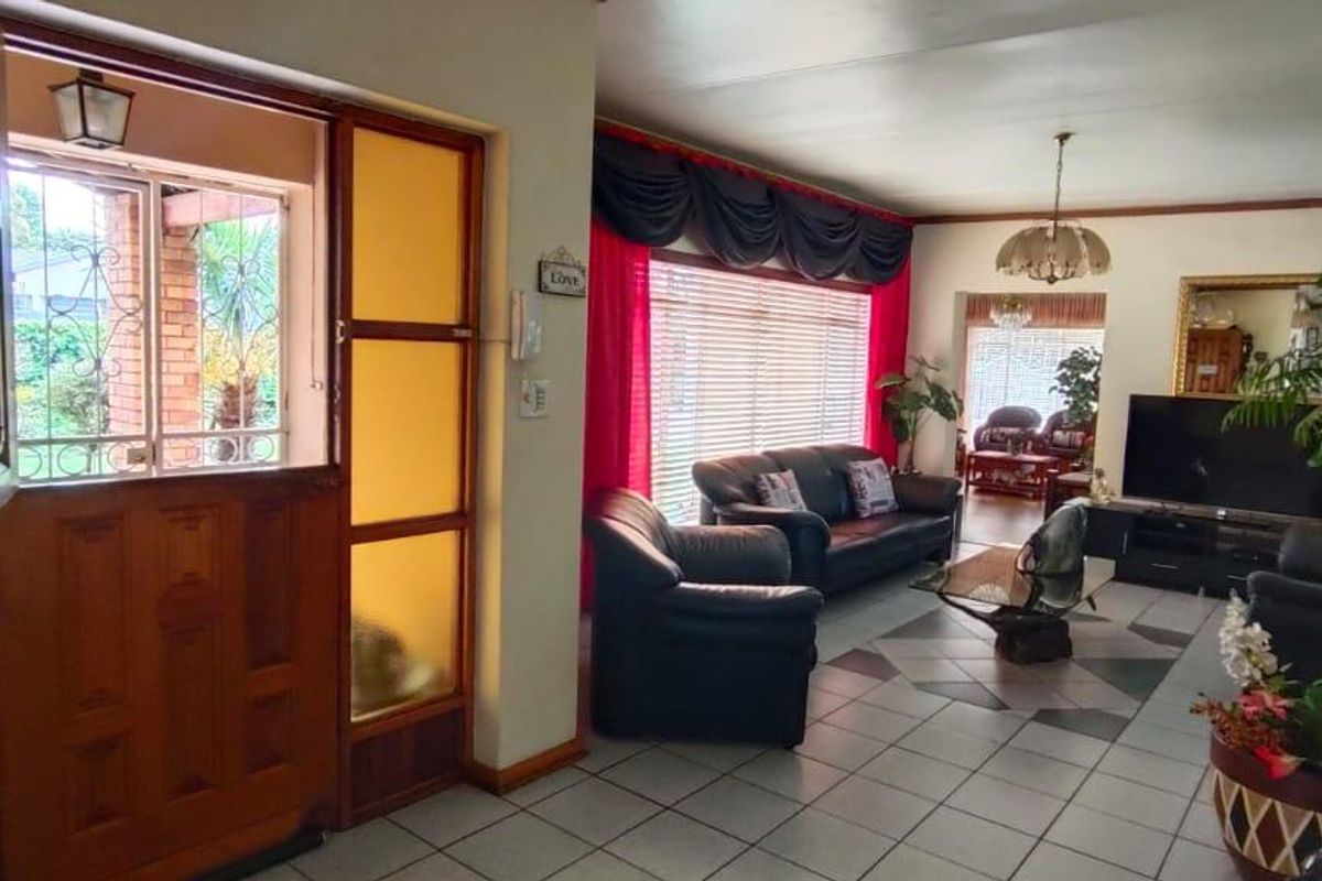 Spacious living area featuring tiled flooring and a traditional timber front door with glass sidelights, offering a bright and welcoming entrance to the home.