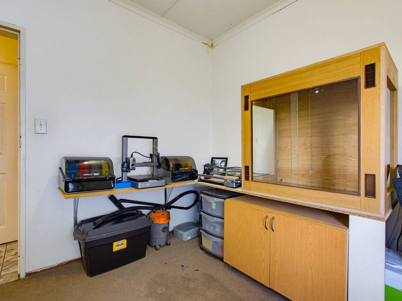 A utility or hobby room featuring built-in cabinetry and wall-mounted shelving, showing signs of ceiling water damage in the corner.