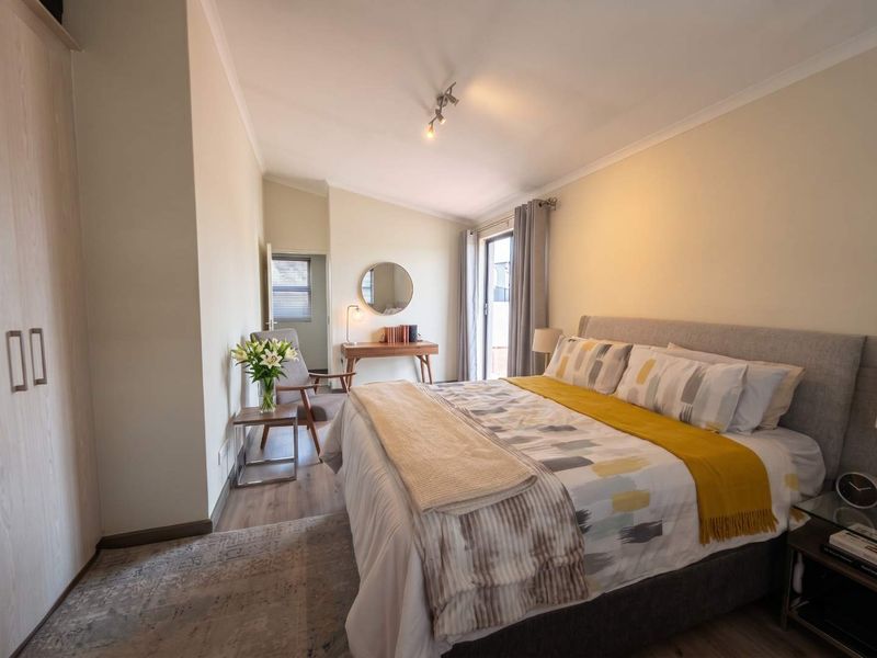 A well-maintained bedroom featuring laminate flooring, built-in wardrobes, and a sliding glass door providing natural light and access to the exterior.