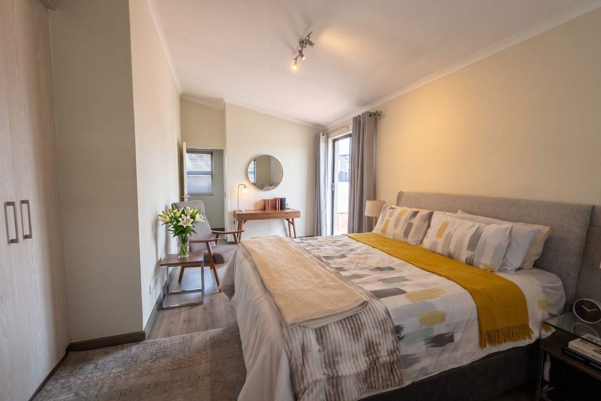 A well-maintained bedroom featuring laminate flooring, built-in wardrobes, and a sliding glass door providing natural light and access to the exterior.