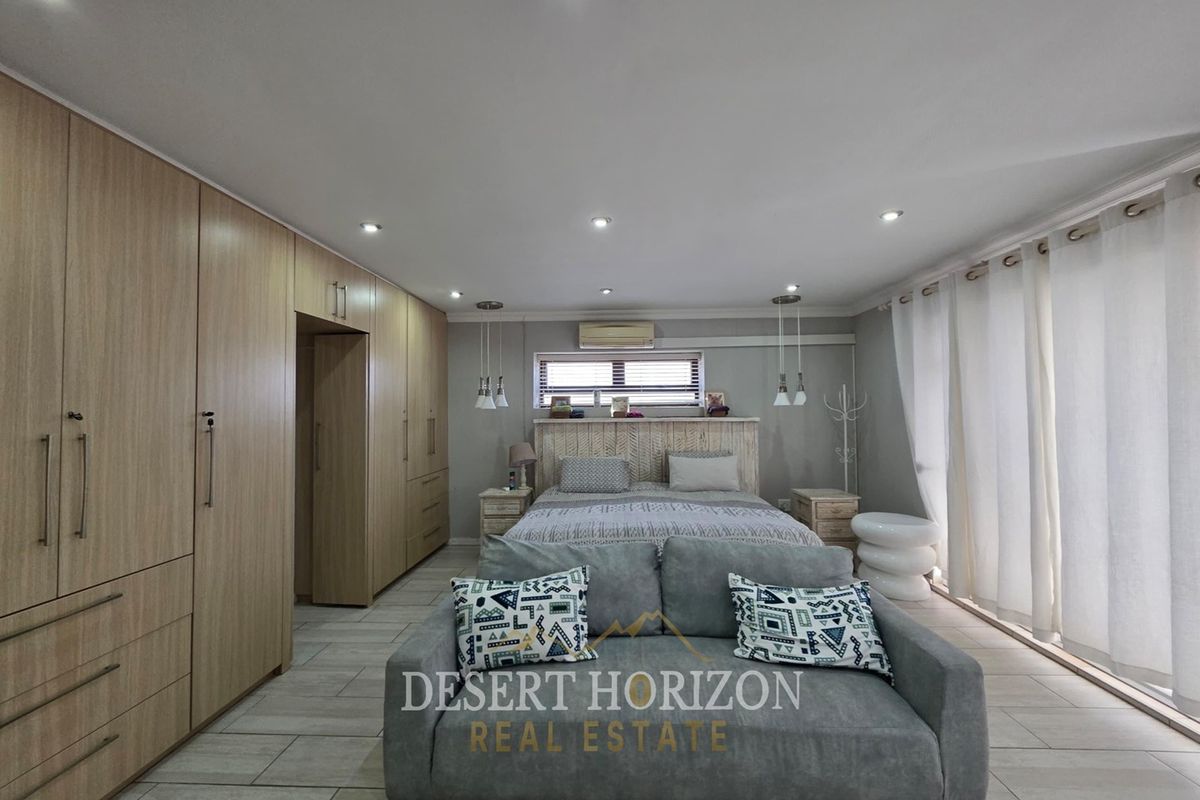 Spacious bedroom featuring extensive built-in cabinetry, tiled flooring, recessed lighting, and large sliding doors providing ample natural light.