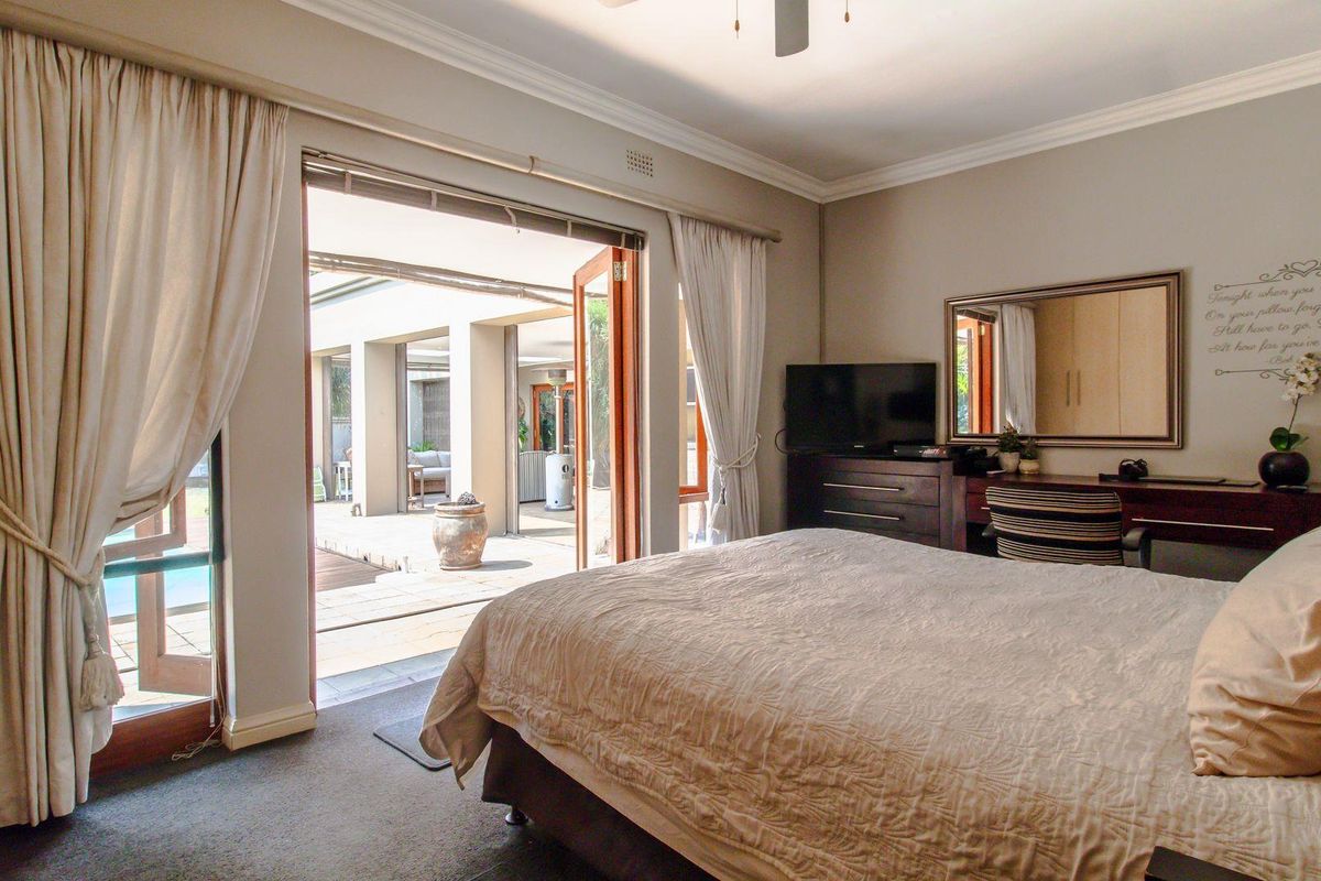 Spacious bedroom featuring neutral tones, crown molding, and large sliding glass doors that open directly onto a patio area.