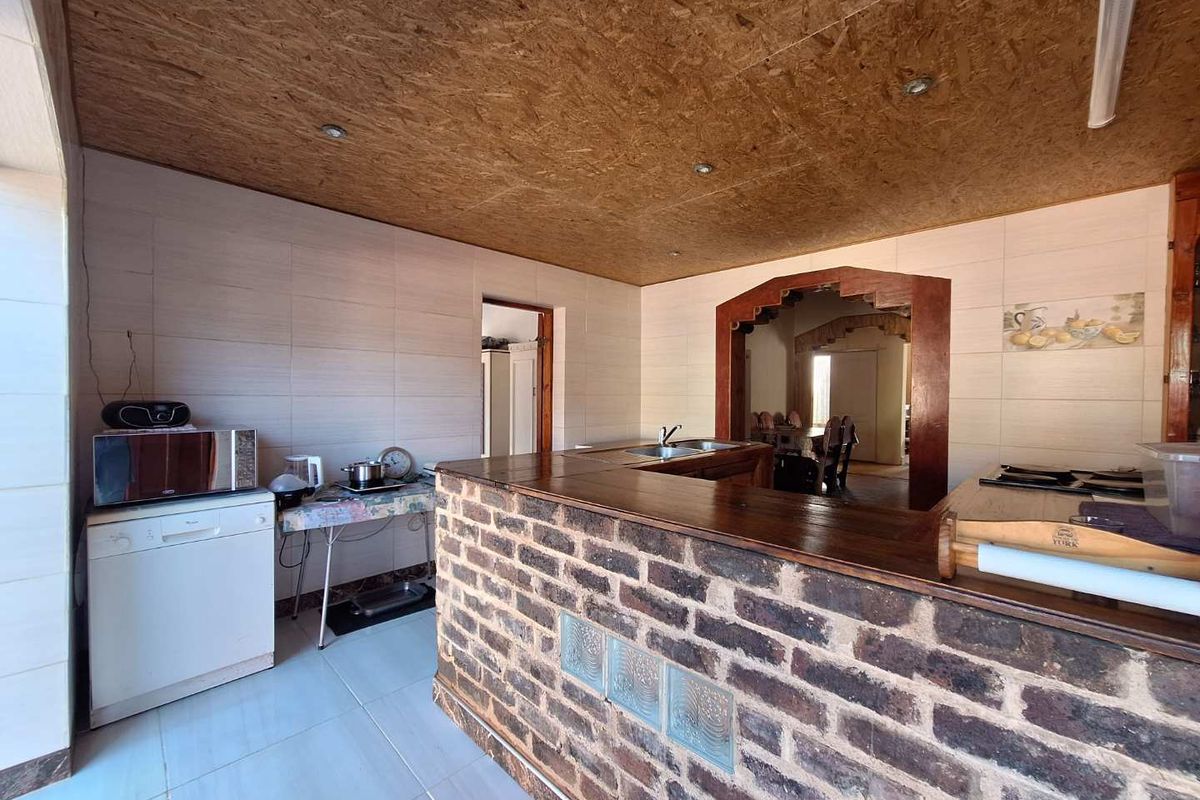 Kitchen area featuring a rustic brick breakfast bar, tiled walls, and an OSB wood-paneled ceiling with integrated downlights.