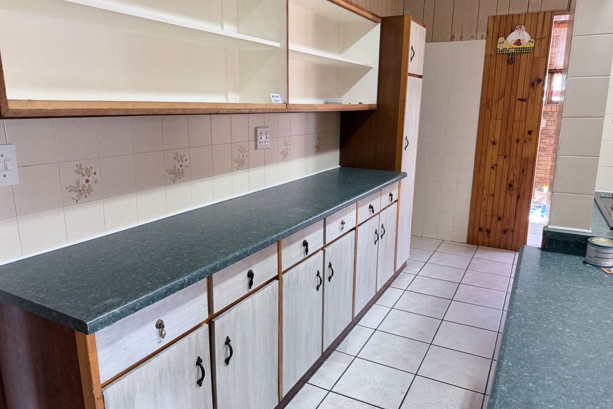 A functional kitchen space featuring extensive laminate cabinetry, durable countertops, and tiled flooring, offering a blank canvas for modern renovation and design updates.