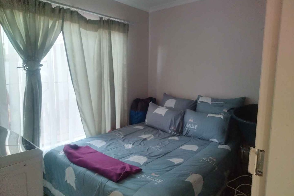 A standard bedroom featuring neutral wall finishes and a window with curtain tracks.