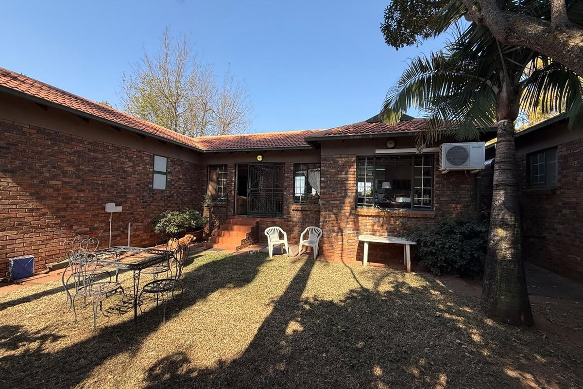 A rear view of the house featuring a face brick facade, tiled roof, and a small garden area with a paved entrance.