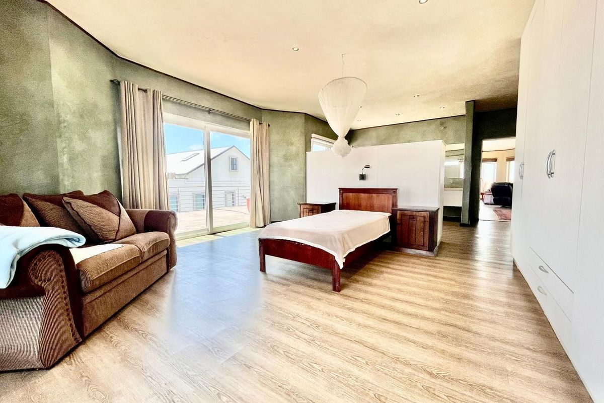 Spacious bedroom featuring wood-look flooring, built-in wardrobes, and sliding glass doors leading to an outdoor balcony area.