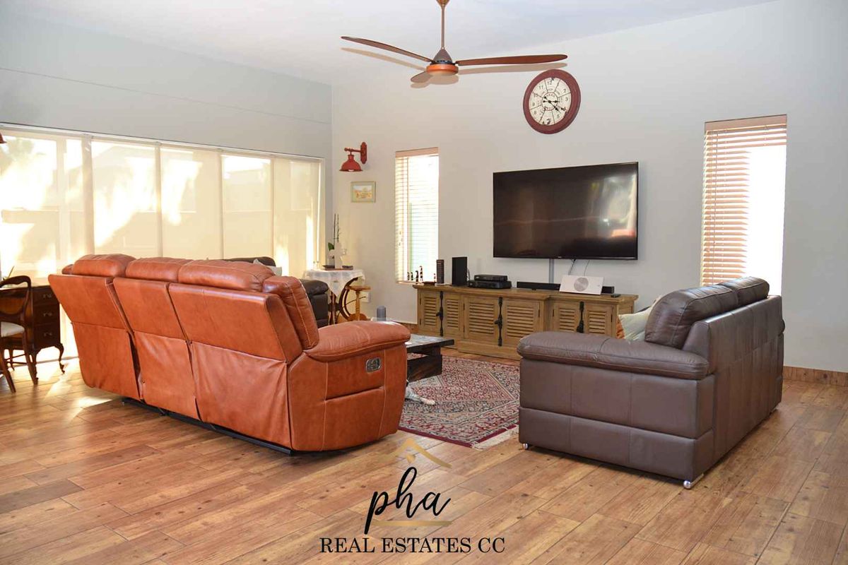 Spacious living room featuring wood-look flooring, a ceiling fan, and large sliding glass doors providing ample natural light.