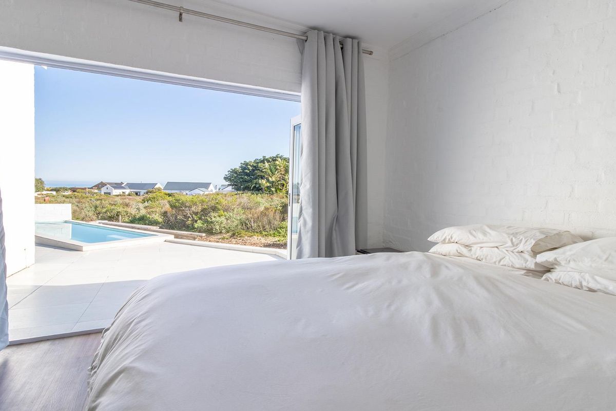 Bright bedroom featuring large sliding glass doors that open directly onto a patio and pool area, offering seamless indoor-outdoor living.