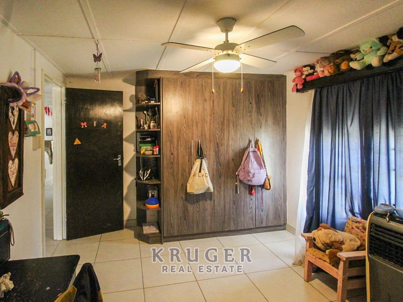 Bedroom featuring built-in wood-finish cabinetry, tiled flooring, and a central ceiling fan.