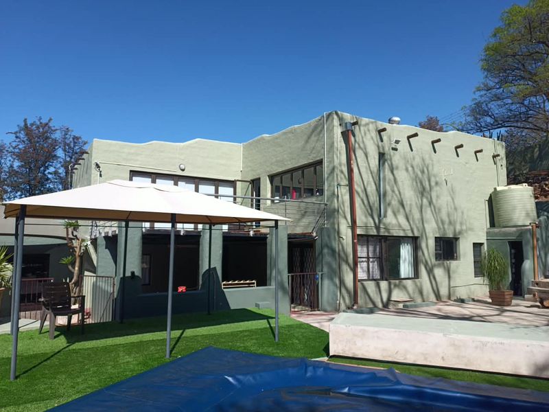 Rear view of the property featuring a swimming pool, artificial lawn area, and a balcony accessible via sliding doors.