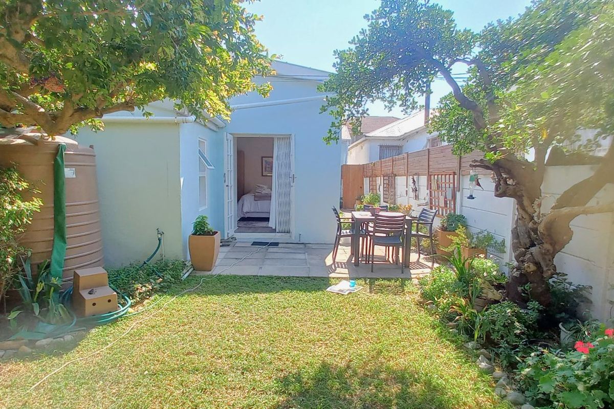 A private rear garden featuring a paved patio area, established trees, a water tank, and secure boundary fencing.