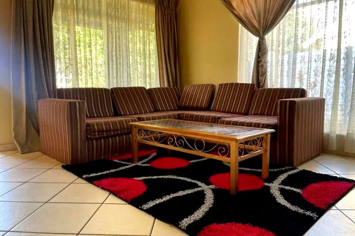 A bright living room featuring large windows with natural light and neutral tiled flooring, offering a comfortable and functional space.
