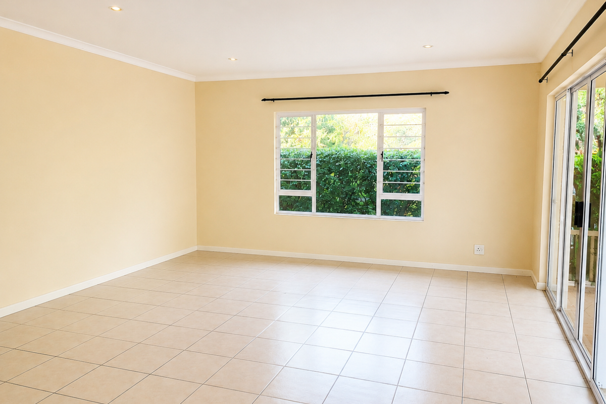 A bright, empty living room featuring neutral tiled flooring, recessed lighting, and large sliding glass doors that provide access to the outdoor area.