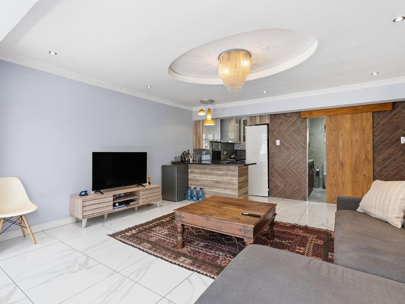 Modern open-plan living area featuring polished porcelain tiles, decorative ceiling lighting, and a stylish wooden sliding door leading to an adjacent space.