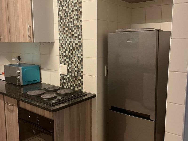 A functional kitchen featuring wood-look cabinetry, granite countertops, a built-in oven and hob, and a decorative mosaic tile backsplash.