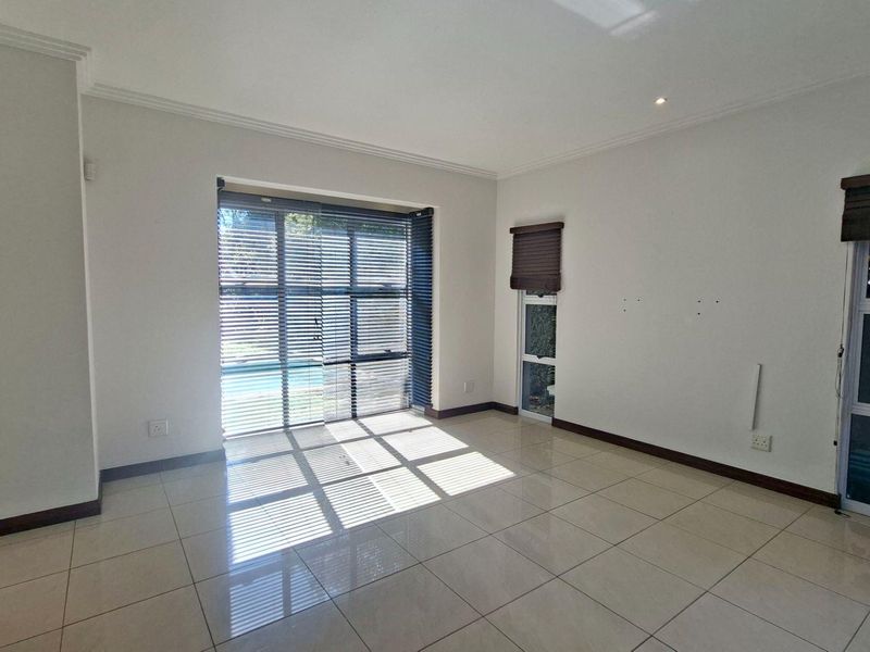 A bright, empty living room featuring large sliding glass doors, tiled flooring, and built-in cabinetry, offering a clean canvas for personalization.