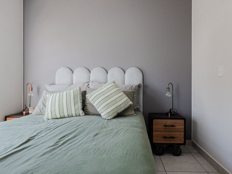 A well-maintained bedroom featuring neutral grey walls and tiled flooring, providing a clean and comfortable living space.