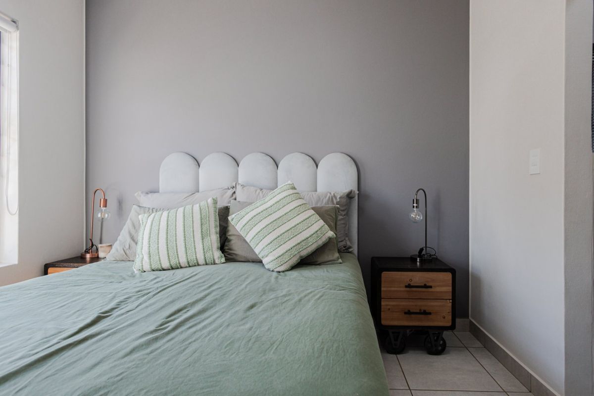 A well-maintained bedroom featuring neutral grey walls and tiled flooring, providing a clean and comfortable living space.