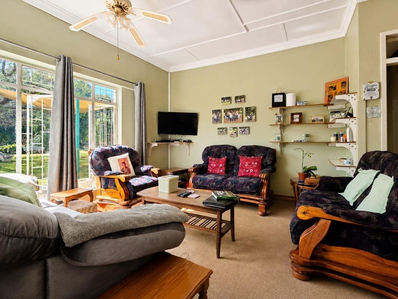 A comfortable living room featuring a coved ceiling, ceiling fan, and large glass sliding doors that provide direct access to the garden.